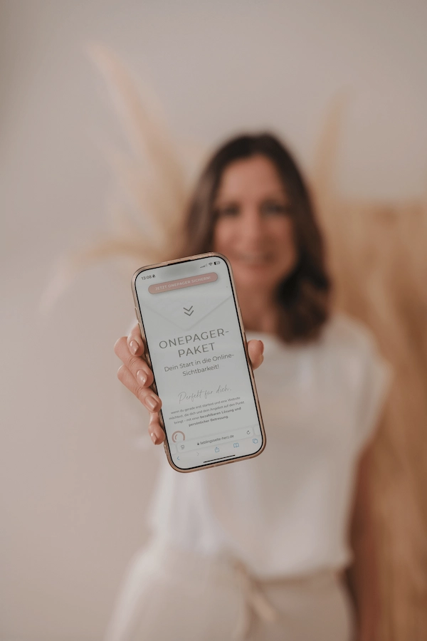 Webdesignerin hält Handy mit Angebotswebsite in der Hand